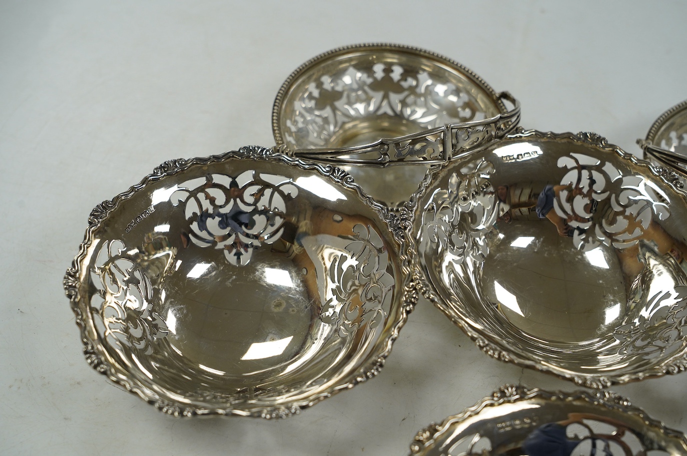 A set of four George VI pierced silver bonbon dishes, by Mappin & Webb, Sheffield, 1938, diameter 12cm and an earlier pair of silver bonbon baskets, 15.7oz. Condition - fair